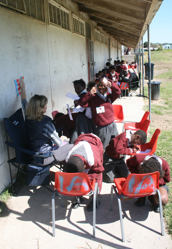 The small groups of learners huddle down the corridor outside the classrooms